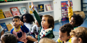 Elementary student raising hand nervously but bravely during class discussion