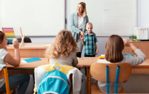 Young happy teacher introduces the new student to the class