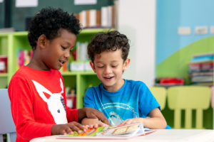 Fifth grade reading buddy helping a first grader sound out words in a picture book